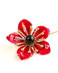 Red enamel poppy flower lapel pin with glossy petals, brass details and black center