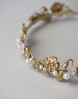 Gold headband with floral and leaf designs on a light gray background