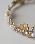 Gold headband with floral and leaf designs on a light gray background