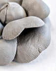 Close-up of grey leather camellia brooch showing layered sculptural form