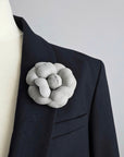 Grey leather camellia brooch worn on black blazer showing scale and styling