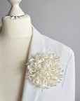 Handcrafted pure ivory silk chrysanthemum brooch pinned on a mannequin blazer lapel by ANTHEMON
