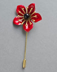 Red flower-shaped brooch on a white background
