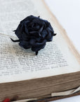 Black rose lapel pin on an open book