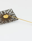 Handmade brass groom boutonniere on white background with filigree detailing