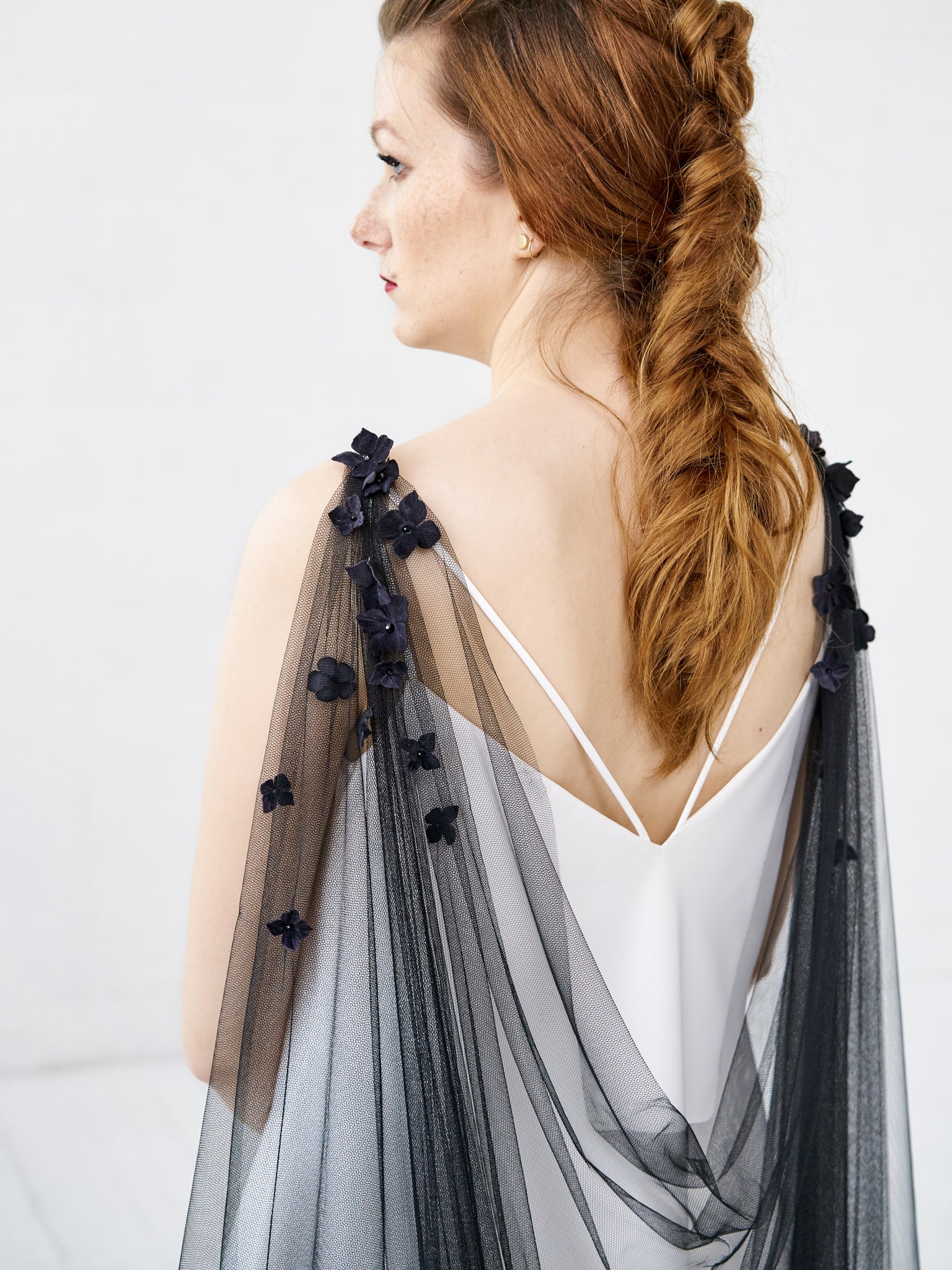 Model wearing SABINE floral cape veil in black, draped across the back