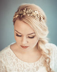 Thalia gold botanical bridal headband featuring dense handcrafted brass leaves and wildflowers with Preciosa pearls, shown on a bride with a blonde side-braid.