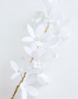 Close-up of handmade bridal hair vine with white blossoms and gold wire