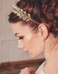 Gold laurel wedding headband with crystals worn in a low bridal updo, side profile view