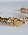Side view of Aegle gold laurel wreath headpiece in natural light with enamel flowers
