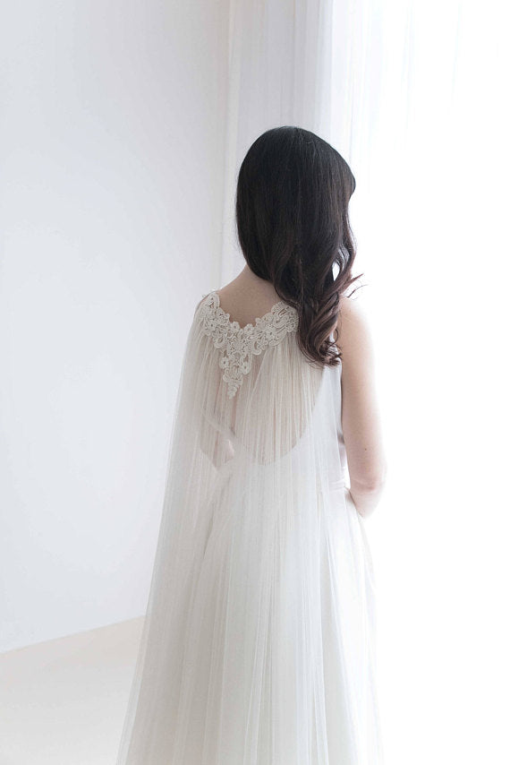 Bride wearing soft English tulle lace cape veil with open back dress in natural light.