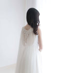 Bride wearing soft English tulle lace cape veil with open back dress in natural light.