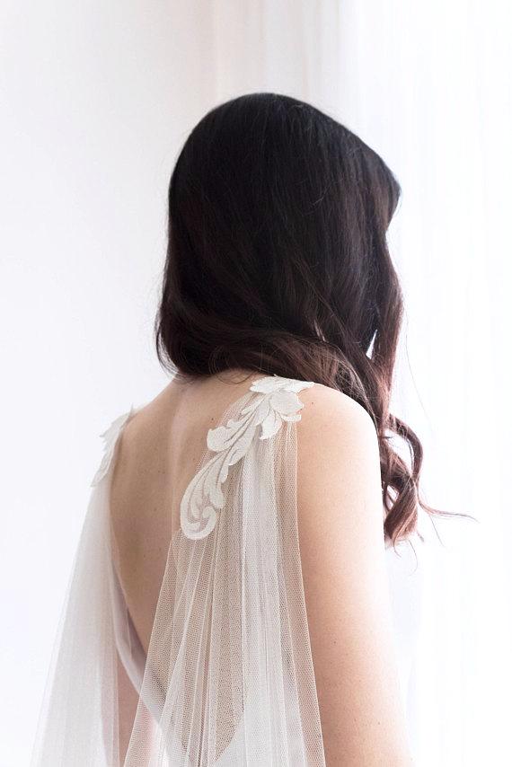 Chapel length cape veil flowing behind bride, showing curved hem with lace edge