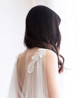 Chapel length cape veil flowing behind bride, showing curved hem with lace edge