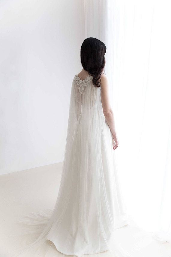 Bride wearing soft English tulle lace cape veil with open back dress in natural light.