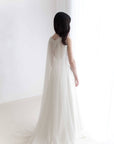 Bride wearing soft English tulle lace cape veil with open back dress in natural light.