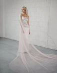 Bride wearing the Phila Cape Veil with a blush ombre effect, draping elegantly over her ivory wedding gown. A chic and unique alternative to a traditional veil.