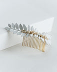 Close-up of hand-enameled laurel leaves with pearl and crystal accents on a bridal hair comb