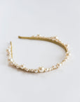 Close-up of handcrafted pearl bridal tiara showing scalloped rows of pearls and fine crystal accents on a metal headband