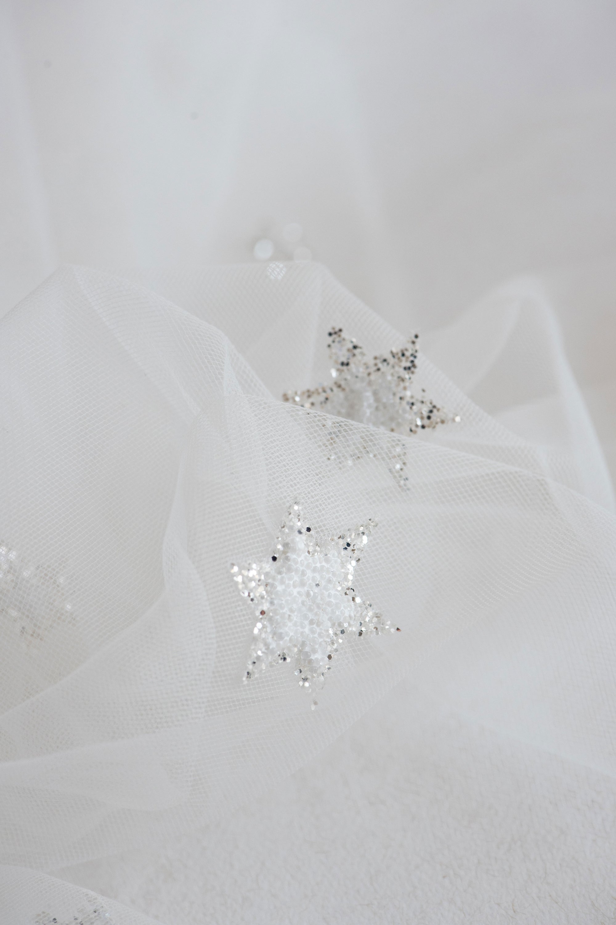 Close-up of beaded star appliqués with silver glitter on Italian tulle – COELESTINE celestial bridal veil