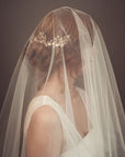 Fine art bridal portrait of a bride seen through a sheer tulle veil, wearing the TYCHE gold leaf hair vine comb for a romantic, ethereal wedding look.