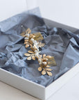 The TYCHE gold bridal hair vine with brass leaves and pearls presented in a white gift box with grey tissue paper, ready for shipping.