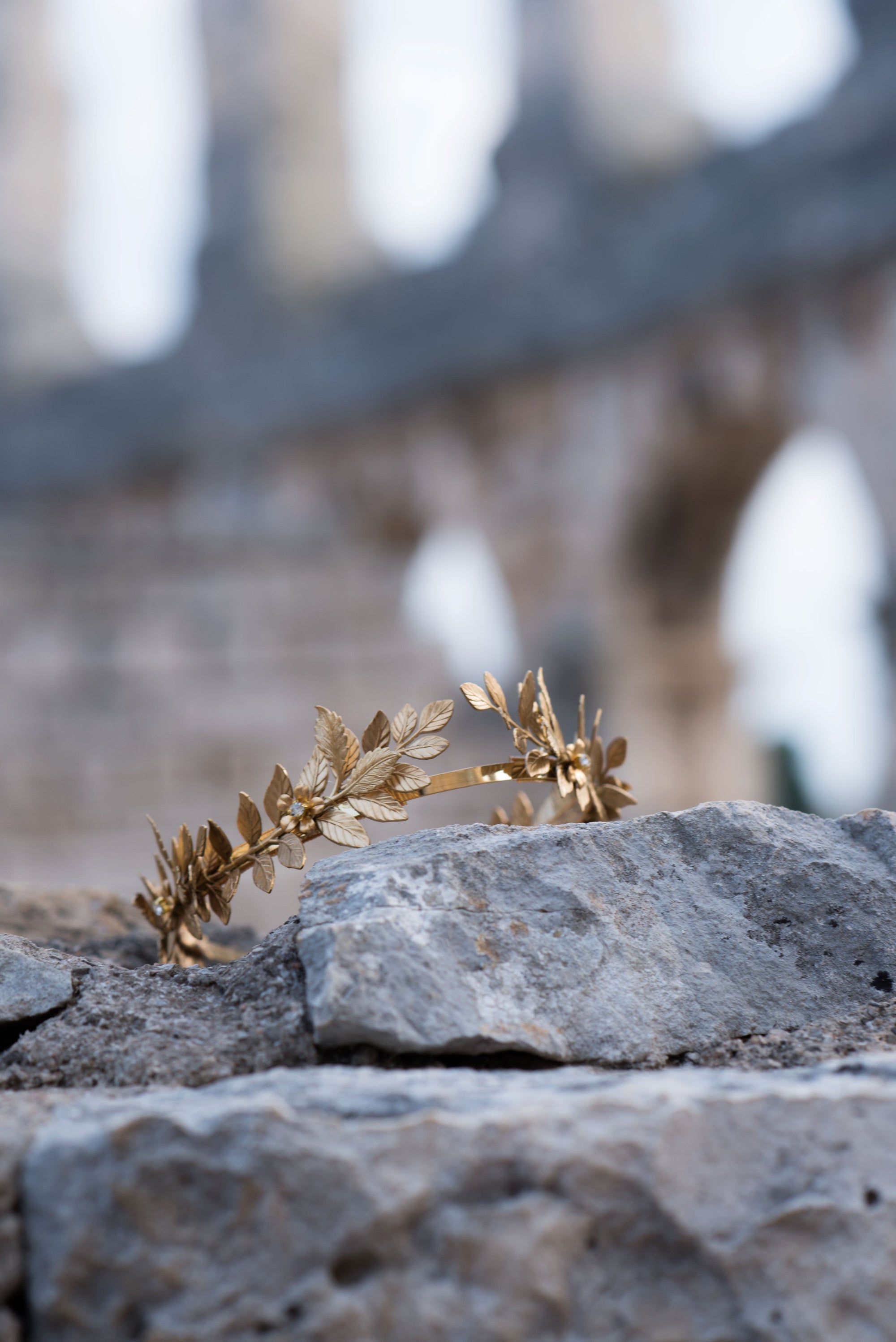 Handcrafted gold laurel leaf bridal headband displayed on stone ruins, symbolic non-traditional bridal accessory