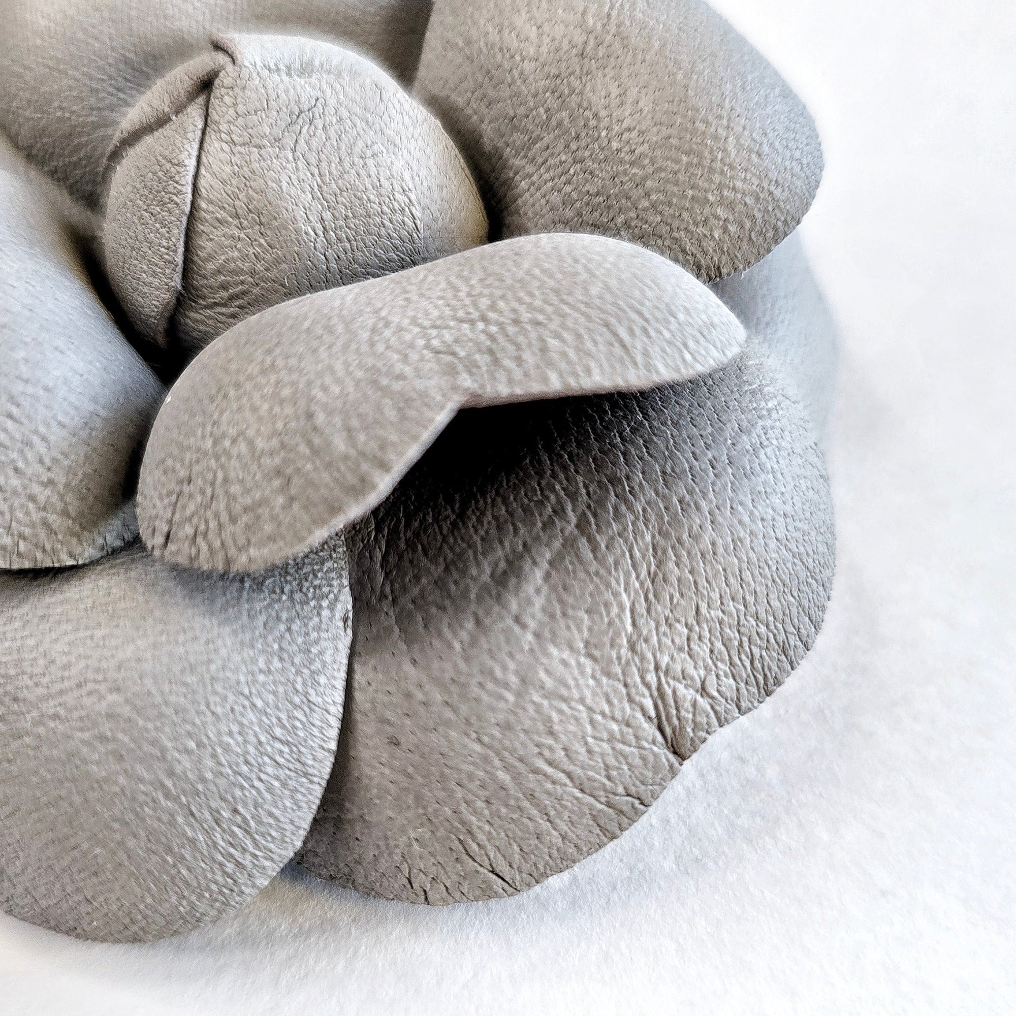 Close-up of grey leather camellia brooch showing layered sculptural form