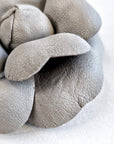Close-up of grey leather camellia brooch showing layered sculptural form