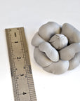 Gray leather caellia brooch next to a ruler on a white background