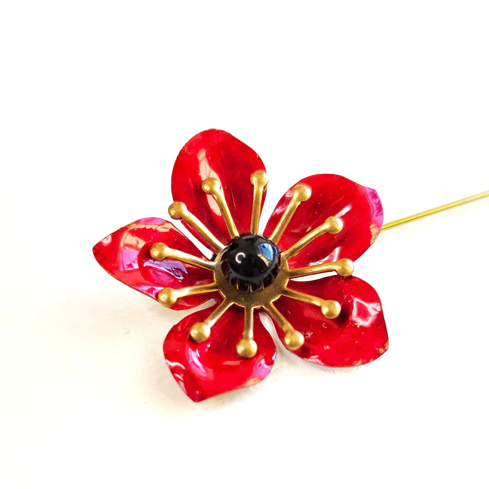 Red enamel poppy flower lapel pin with glossy petals, brass details and black center