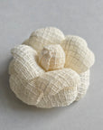 Ivory tweed camellia brooch pin on light background, elegant wedding accessory