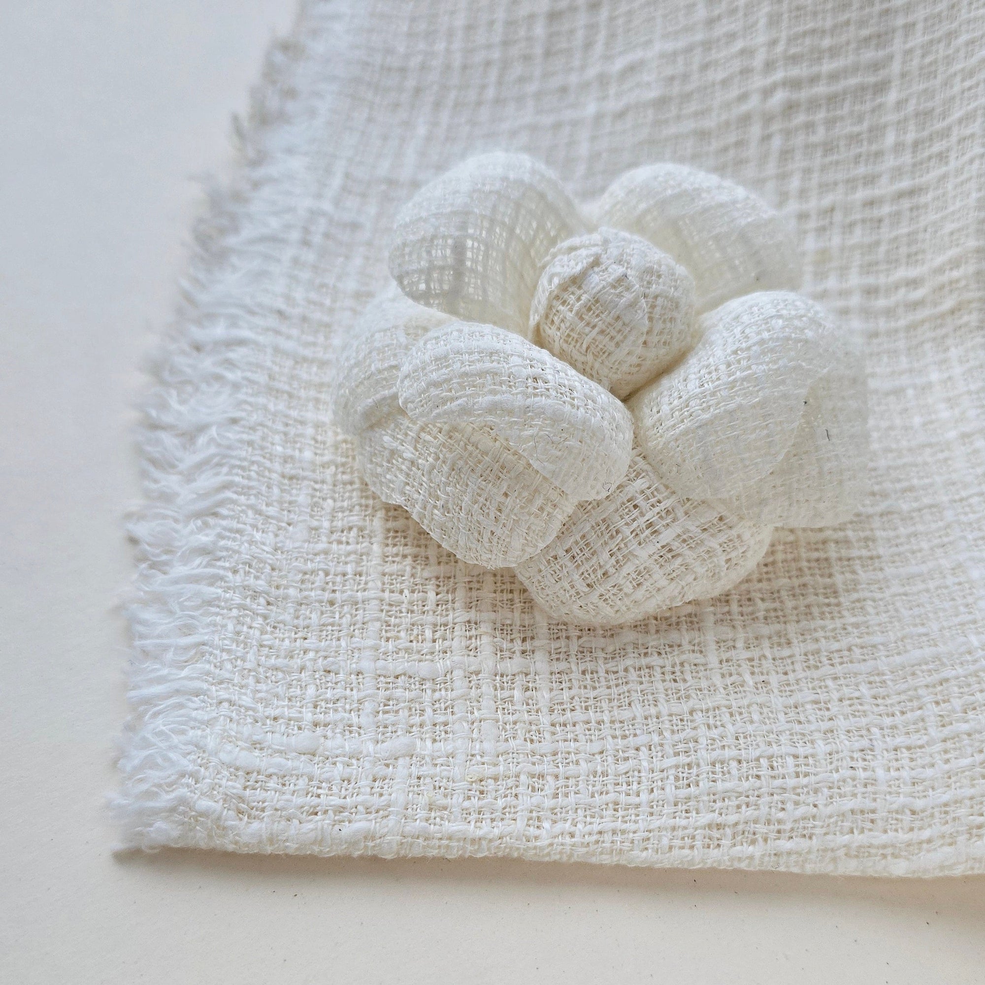 Ivory tweed camellia fabric flower brooch, photographed with the original tweed textile