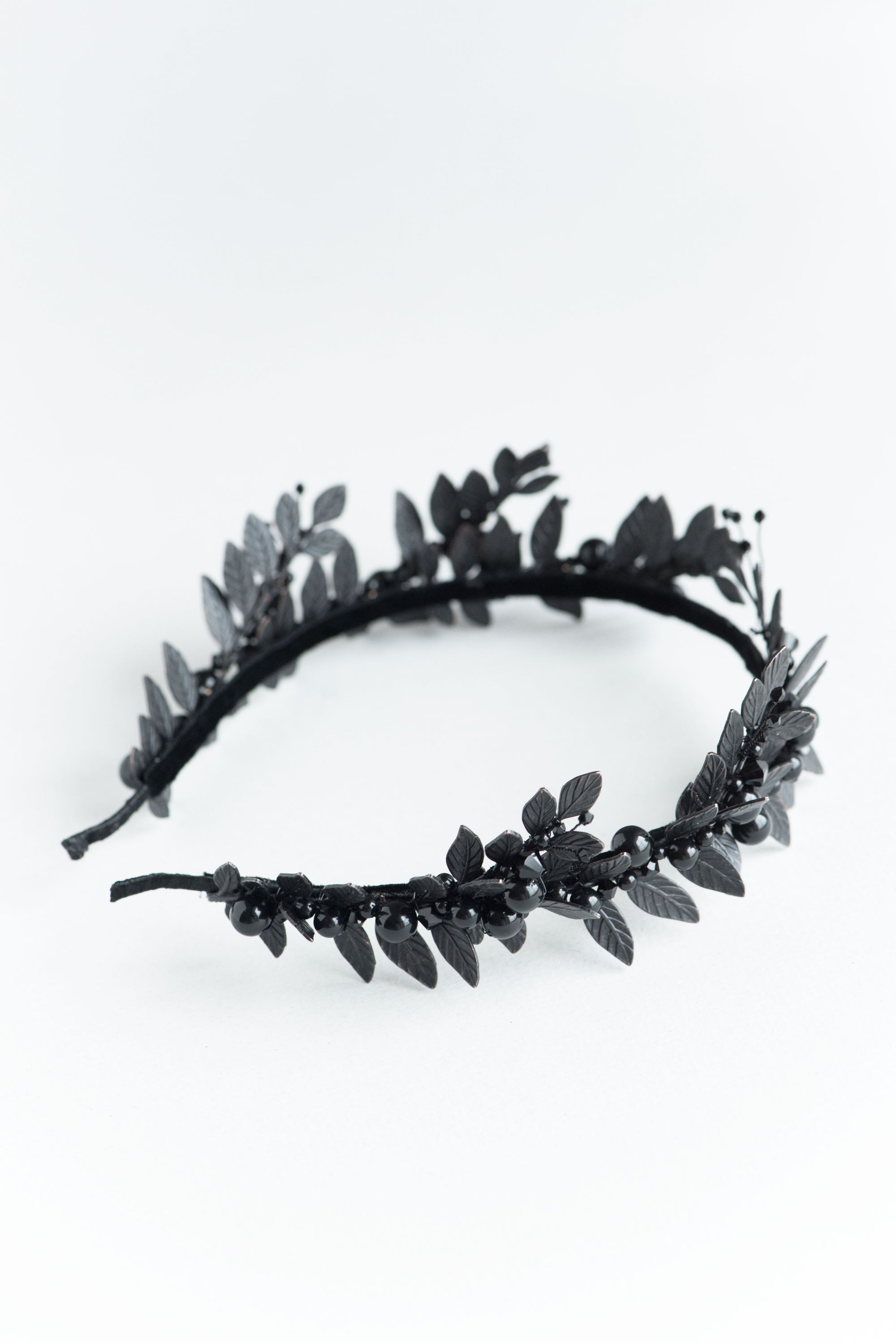 Angled view of the LZZY black headpiece, highlighting the non-reflective matte finish of the brass laurel leaves and pearl accents
