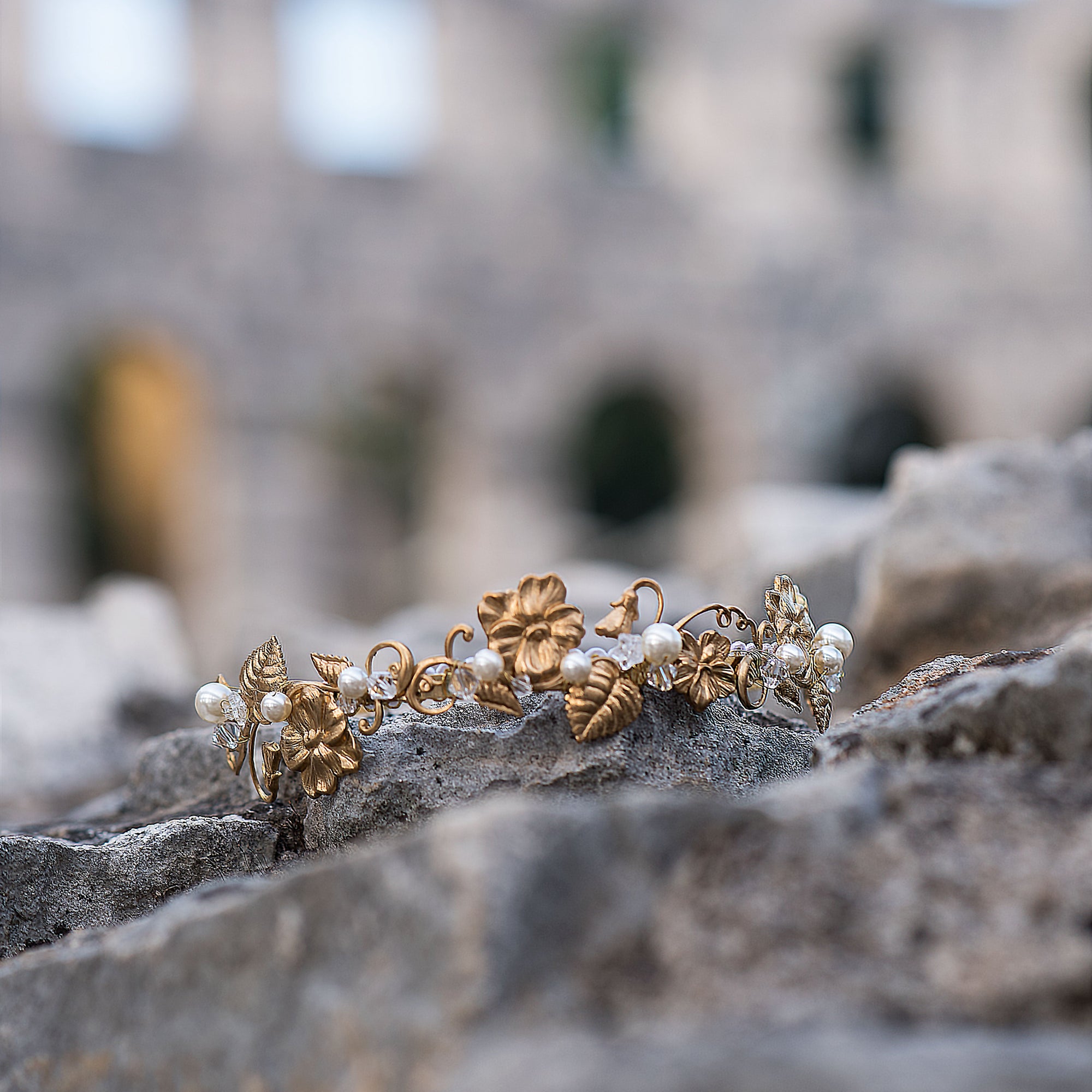Gold and pearl headband on stone surface with blurred ancient architecture in the background