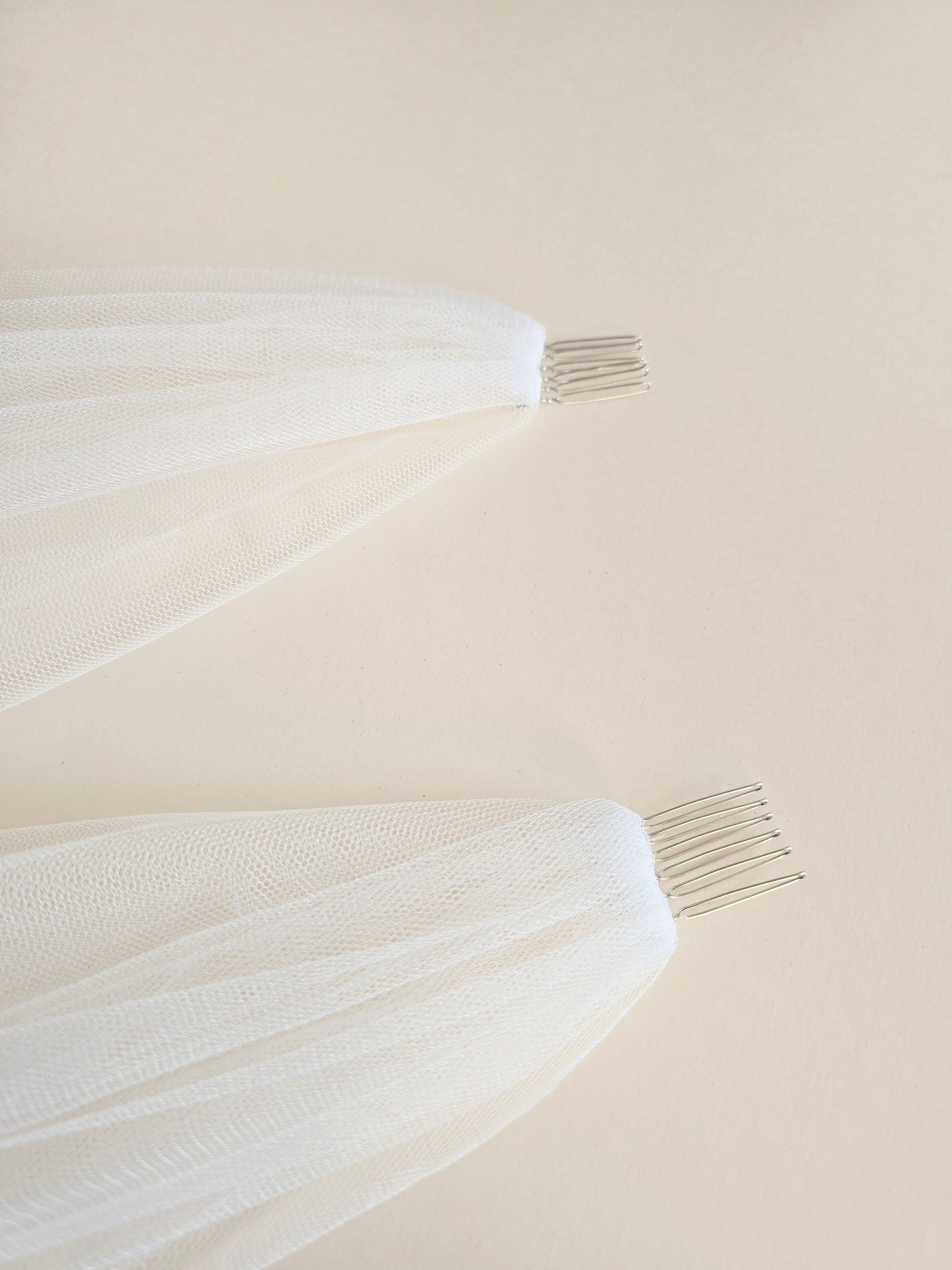 Close-up of discreet hand-sewn metal combs and raw-cut edge of Elizabeth wedding veil, matte ivory finish.