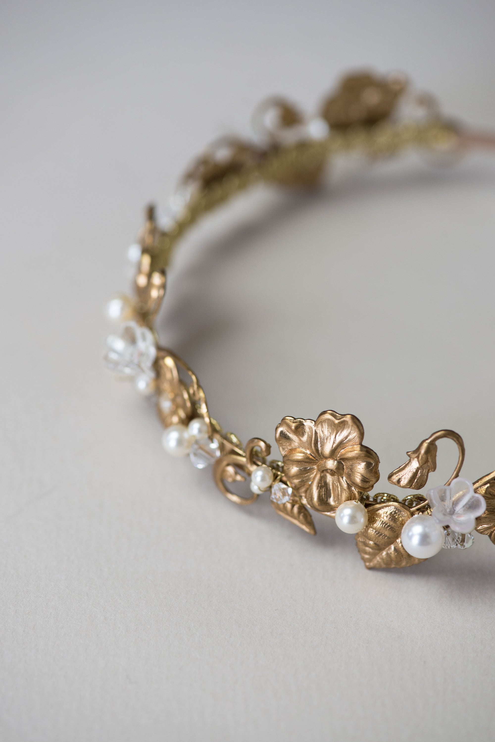 Gold headband with floral and leaf designs on a light gray background