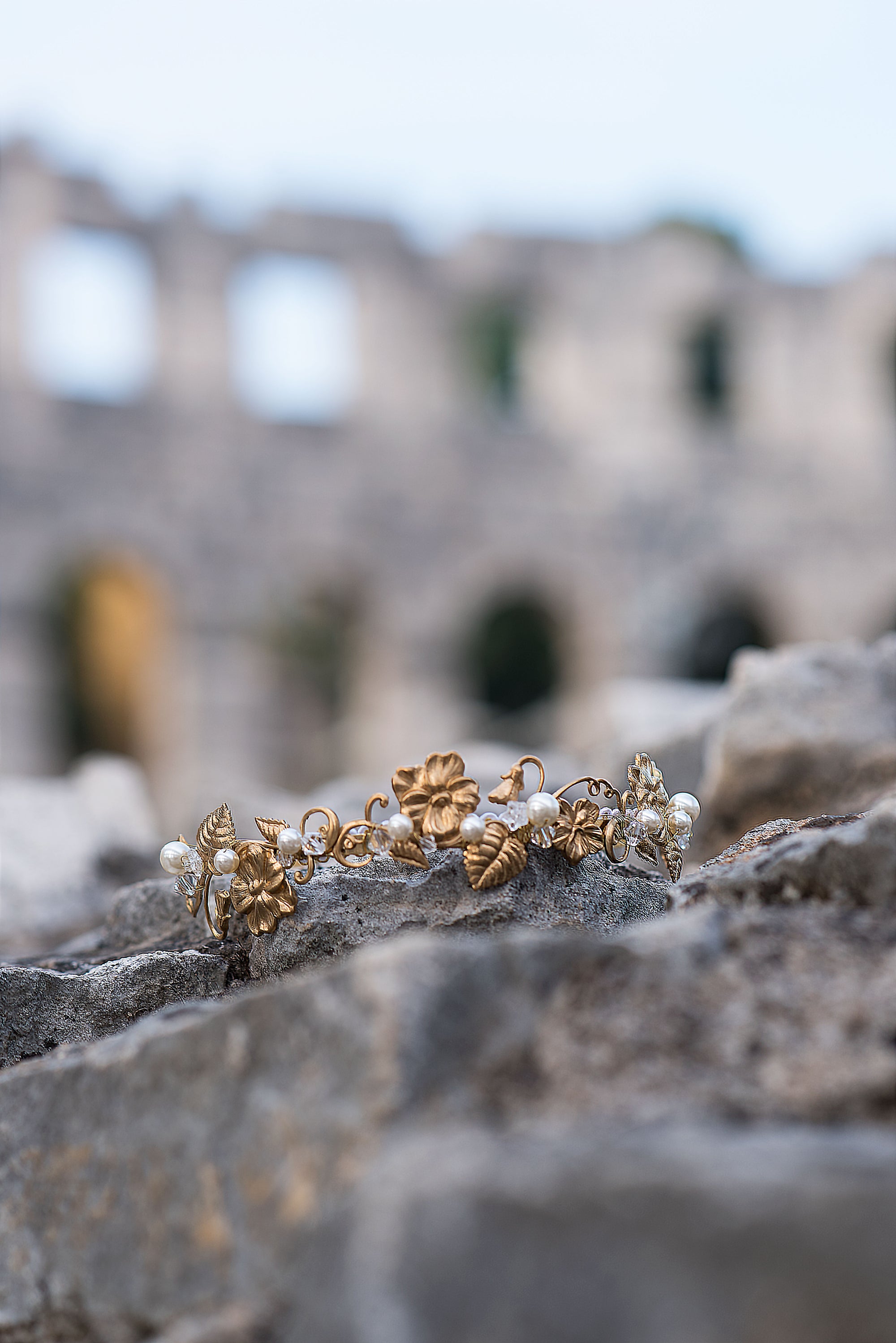 Gold and pearl headband on stone surface with blurred ancient architecture in the background