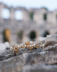 Gold and pearl headband on stone surface with blurred ancient architecture in the background