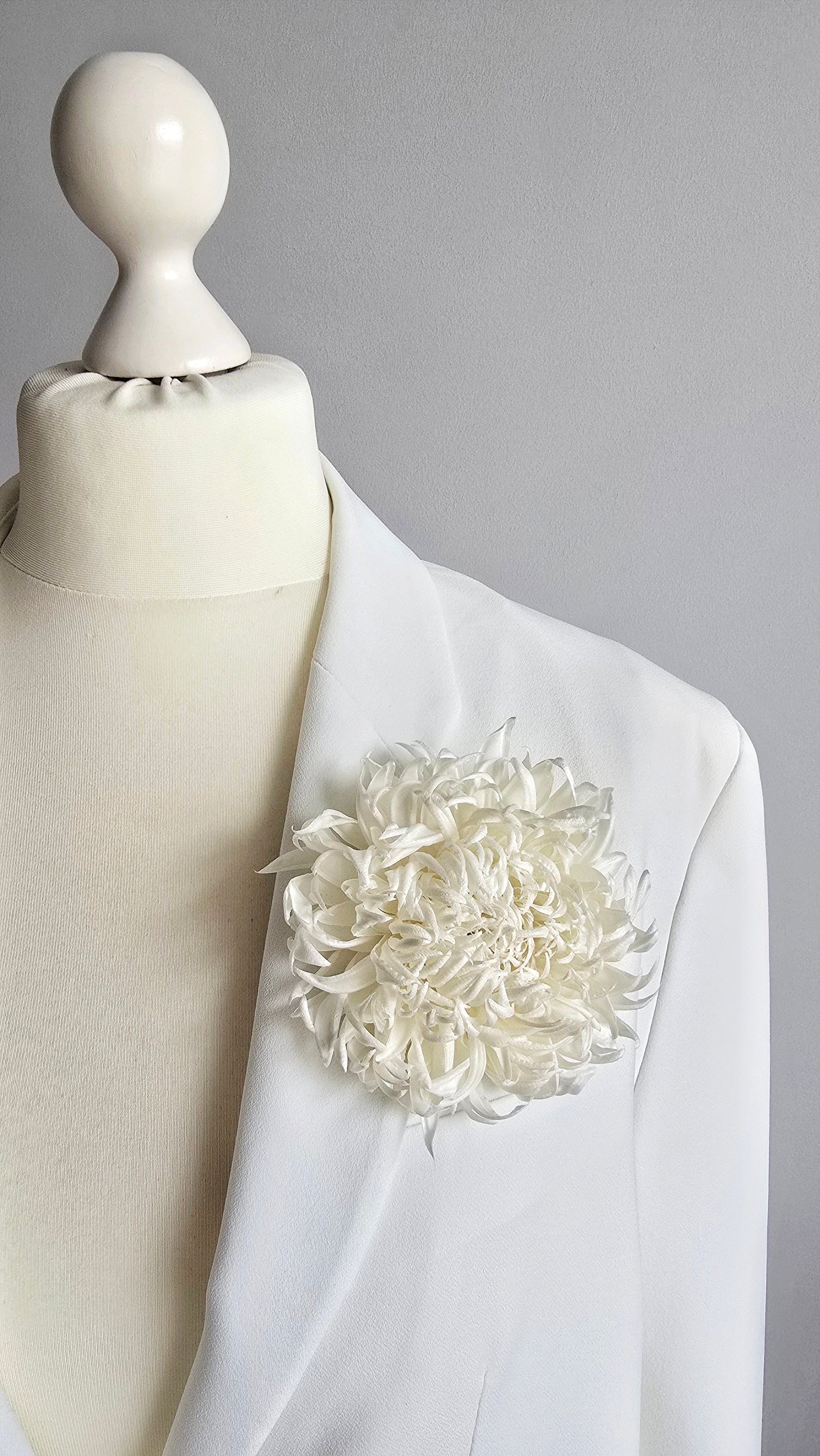 Handcrafted pure ivory silk chrysanthemum brooch pinned on a mannequin blazer lapel by ANTHEMON