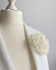 Side view of pure ivory silk chrysanthemum statement pin styled on white bridal coat