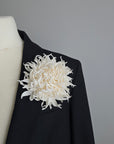 Pure ivory silk chrysanthemum brooch styled on a dark black blazer lapel for contrast