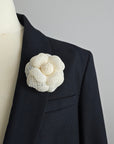 Ivory tweed camellia flower brooch pin detail on a mannequin against a gray background