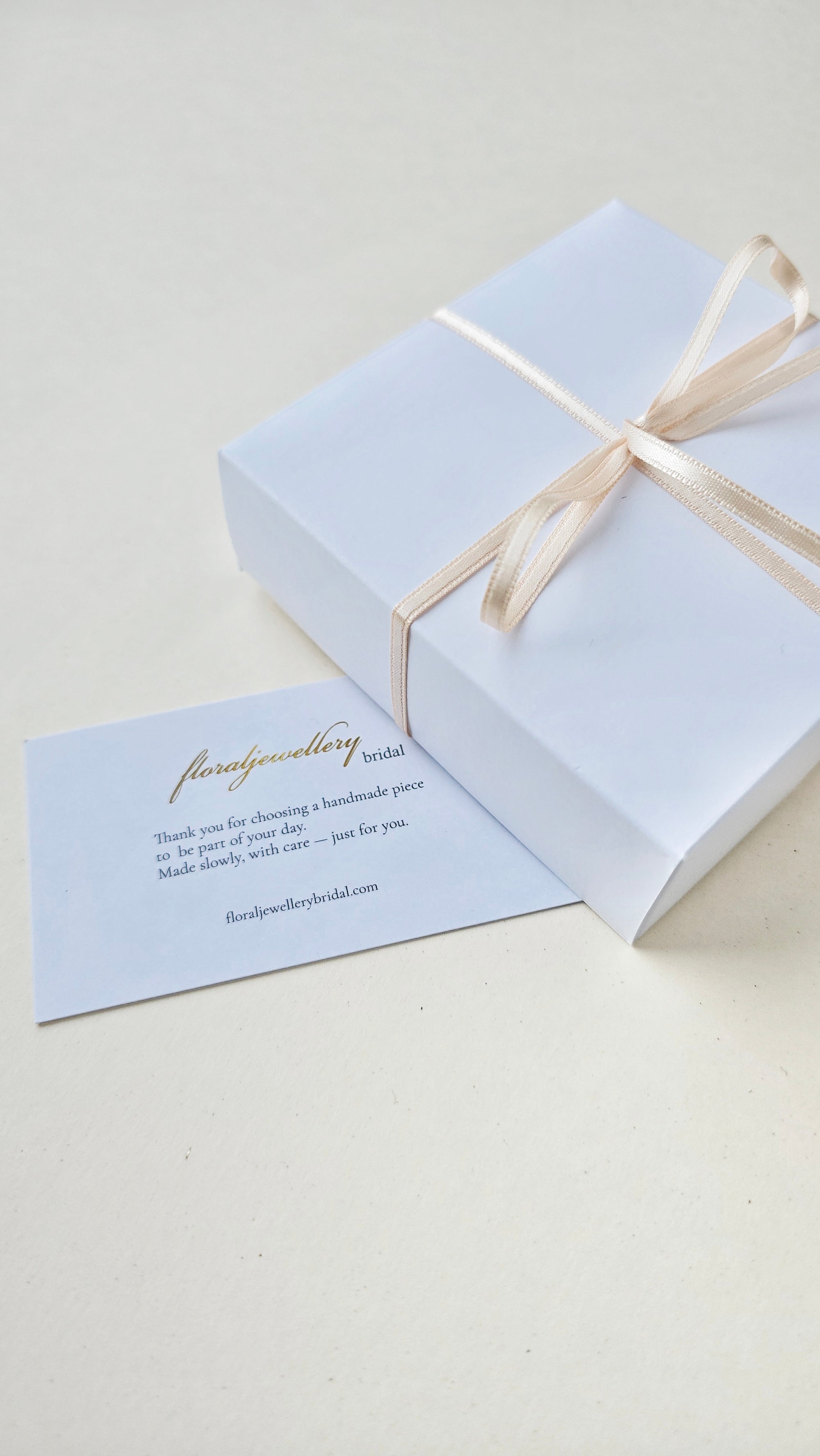 White gift box with a bow and a matching card on a light background