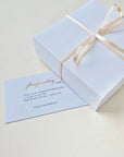 White gift box with a bow and a matching card on a light background