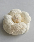 Ivory tweed camellia brooch pin on light background, elegant wedding accessory
