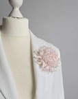 Handcrafted powder pink silk chrysanthemum brooch pinned on a white blazer lapel
