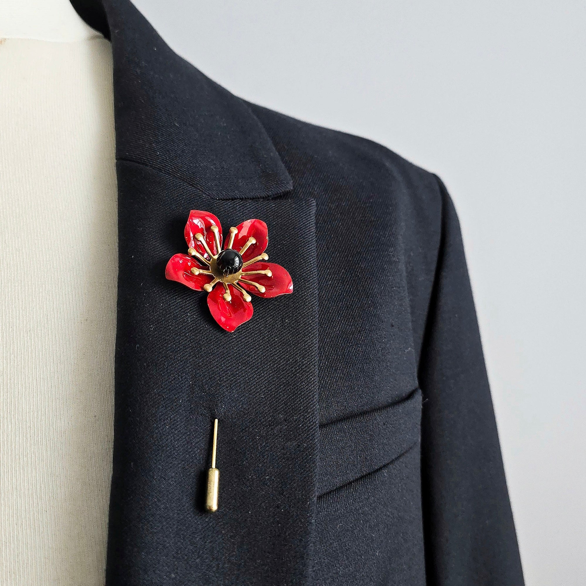 POPPY red enamel pin with black center worn on black lapel mens statement boutonniere