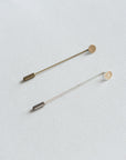 Two small metal pins on a white background