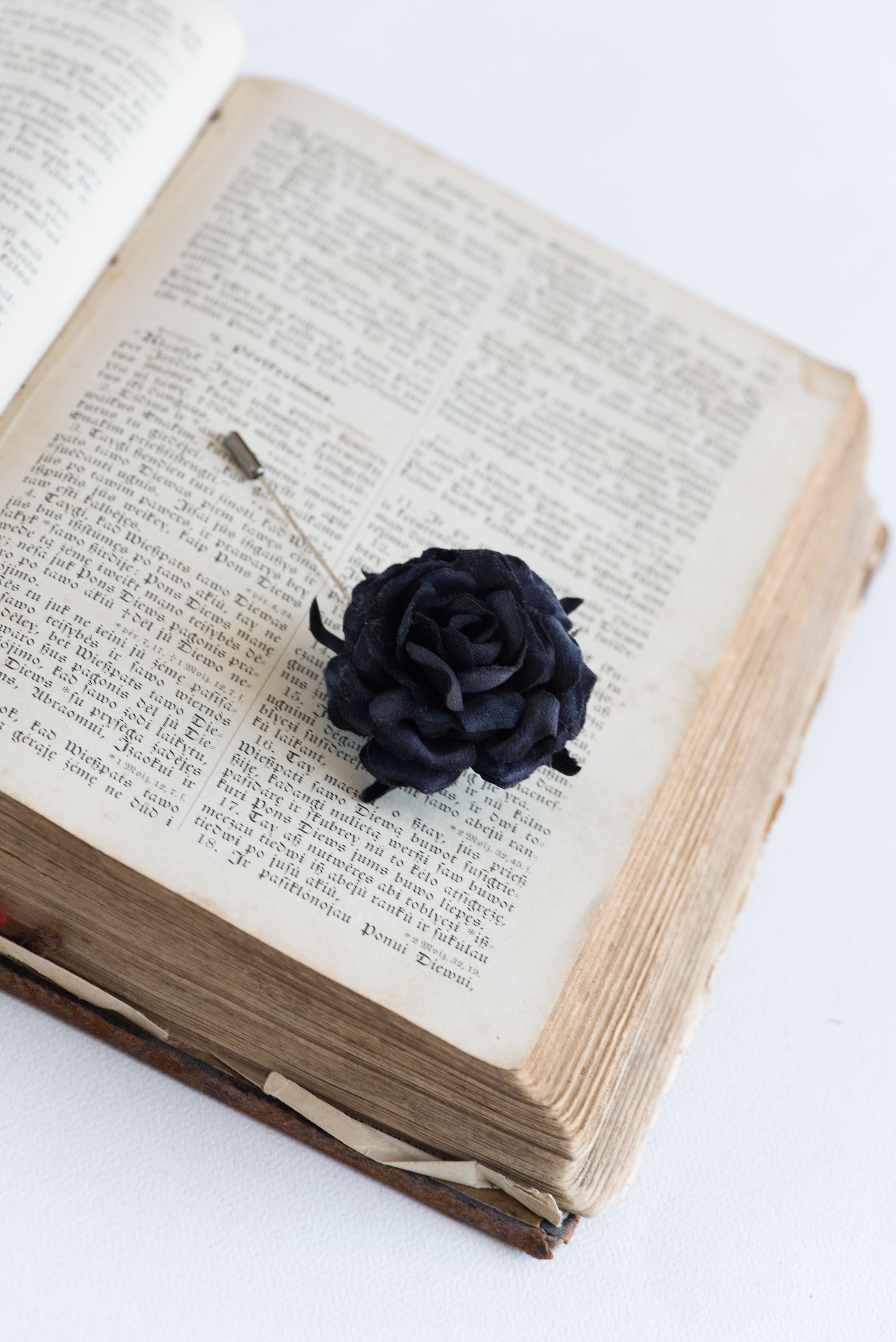 Blacl rose lapel pin on the open book